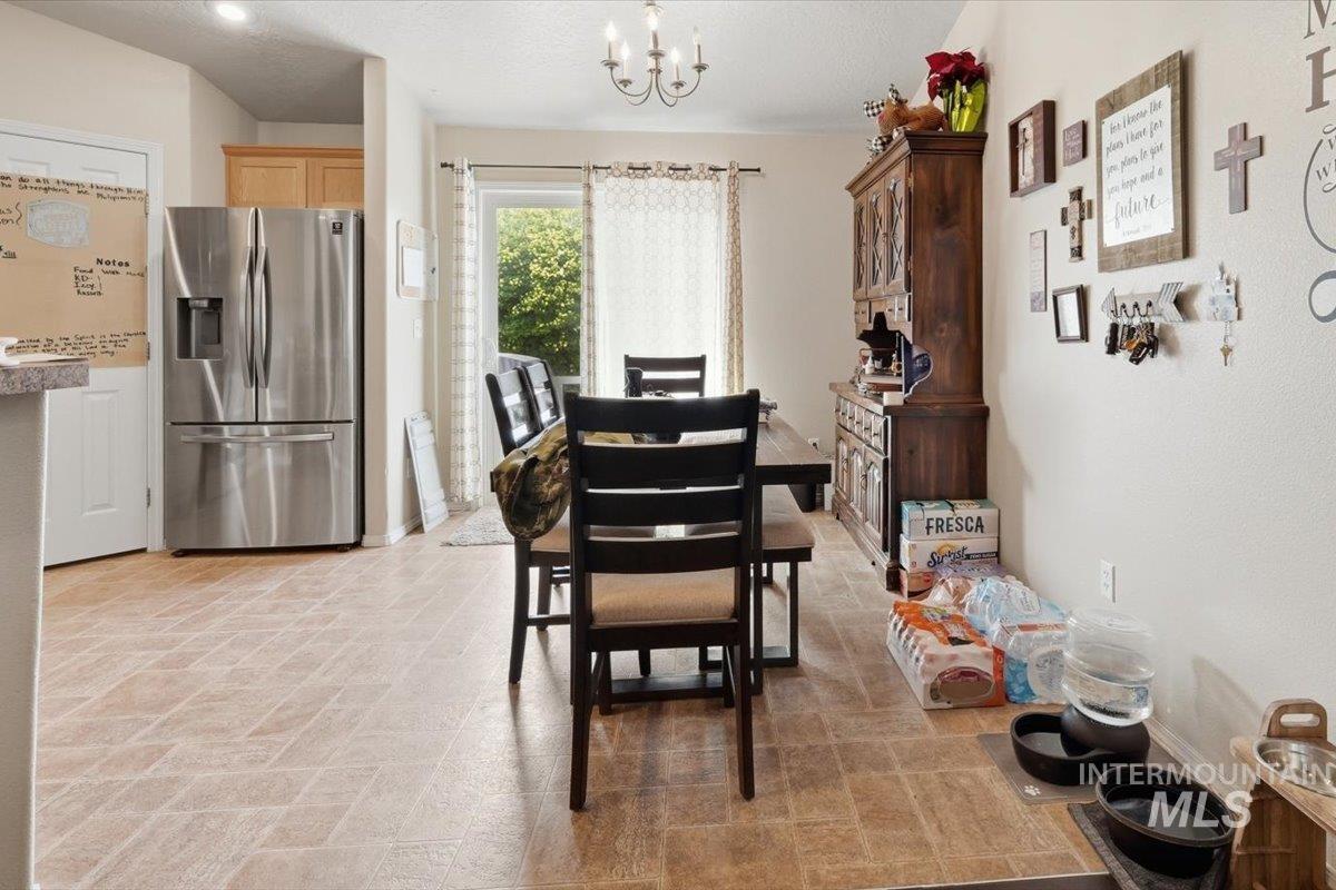 2714 Colfax Drive Caldwell, ID 83607 - Photo 13 of 40 Open-concept kitchen and dining area featuring durable tile-look flooring, a sliding glass door, and a traditional chandelier