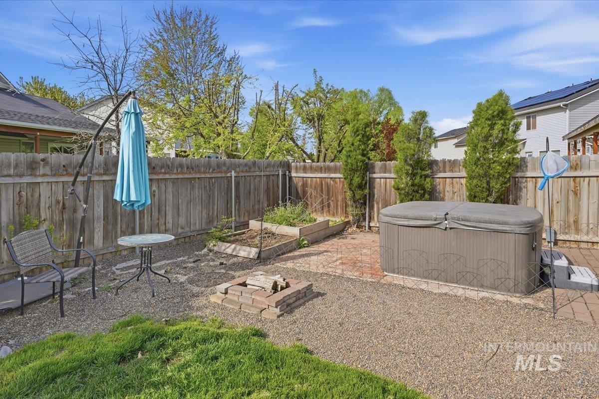 2714 Colfax Drive Caldwell, ID 83607 - Photo 30 of 40 Fenced backyard featuring a gravel and brick patio, built-in hot tub with cover, raised garden beds, and a brick fire pit
