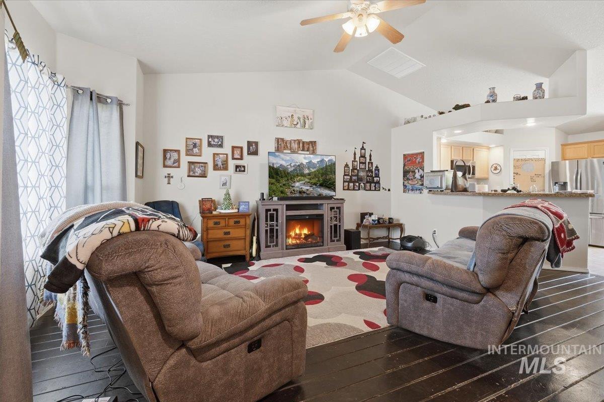 2714 Colfax Drive Caldwell, ID 83607 - Photo 4 of 40 Living area featuring vaulted ceilings, a ceiling fan with integrated lighting, dark wood-finish flooring, and an entertainment console with an electric fireplace