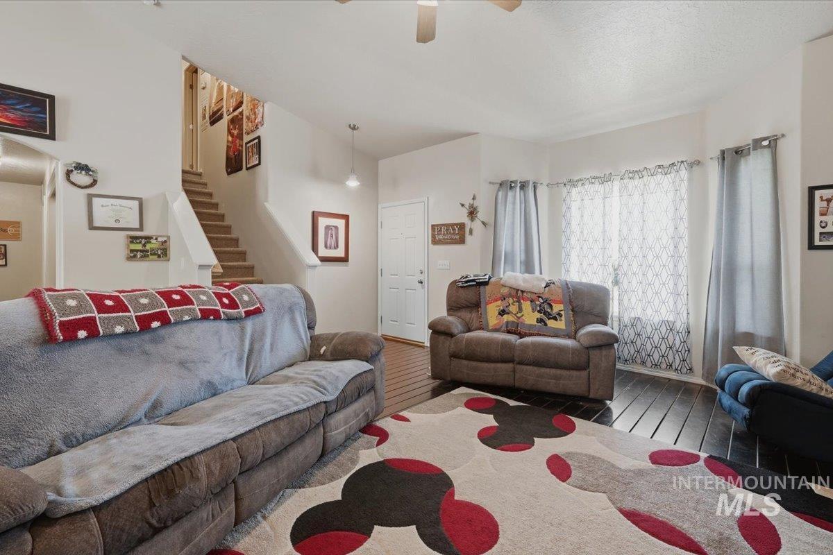 2714 Colfax Drive Caldwell, ID 83607 - Photo 5 of 40 Spacious living area featuring dark wood-finish flooring, a contemporary ceiling fan, and a prominent staircase with light wood treads