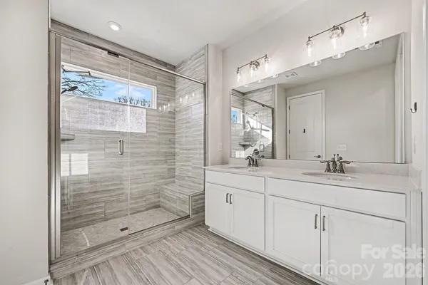 a bathroom with a double vanity sink mirror and shower