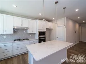 a kitchen with kitchen island a stove a sink a refrigerator and white cabinets