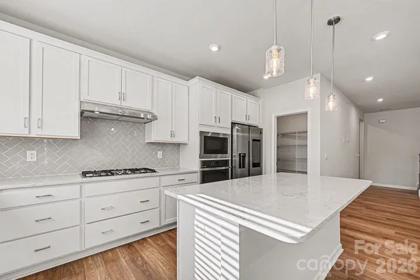 a kitchen with stainless steel appliances kitchen island granite countertop a stove a sink and a refrigerator