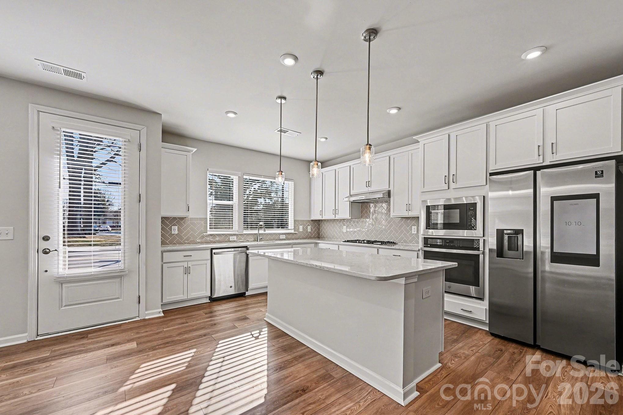5451 Comiskey Alley Kannapolis, NC 28081 - Photo 10 of 27 a kitchen with stainless steel appliances granite countertop a refrigerator a sink dishwasher a stove and white cabinets with wooden floor