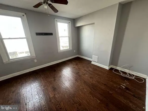 an empty room with wooden floor and a ceiling fan