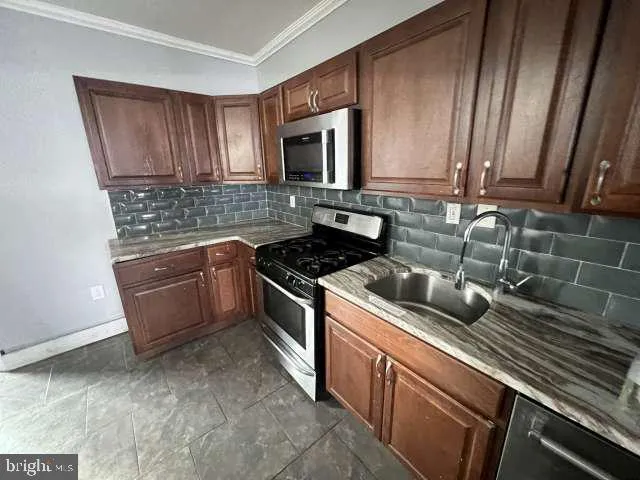 a kitchen with stainless steel appliances a refrigerator a stove a sink a washer dryer and a refrigerator