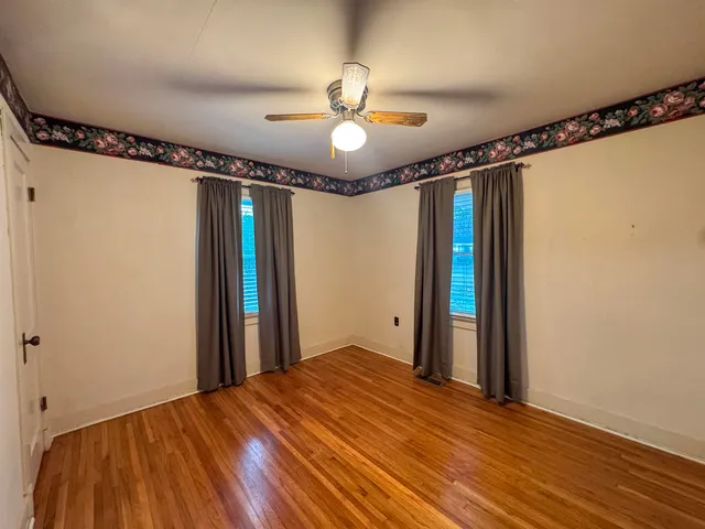 a view of a room with wooden floor fan and windows
