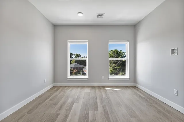 an empty room with wooden floor and windows