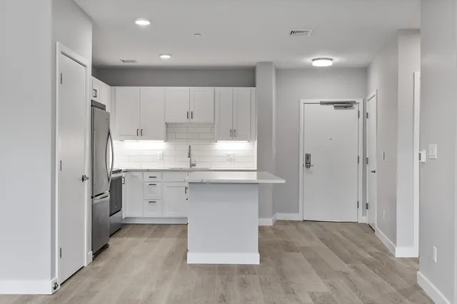 a room view with wooden floor cabinetry and a refrigerator