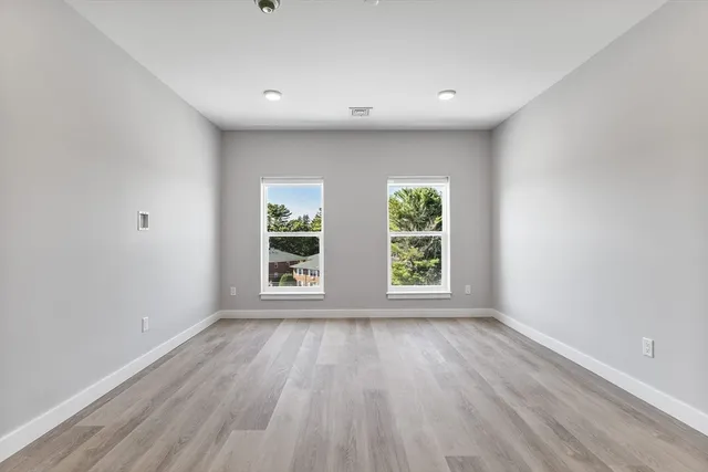 an empty room with wooden floor and windows