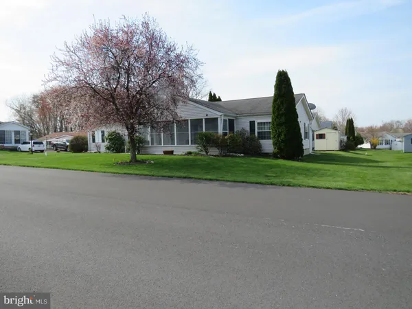 a view of a white house next to a yard with big trees