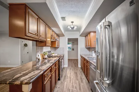 a kitchen with stainless steel appliances granite countertop a refrigerator a stove and a sink with cabinets