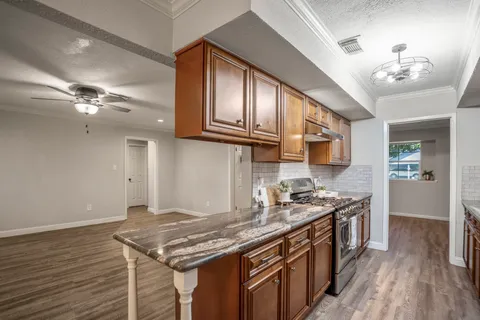a kitchen with stainless steel appliances granite countertop a stove and a wooden floors