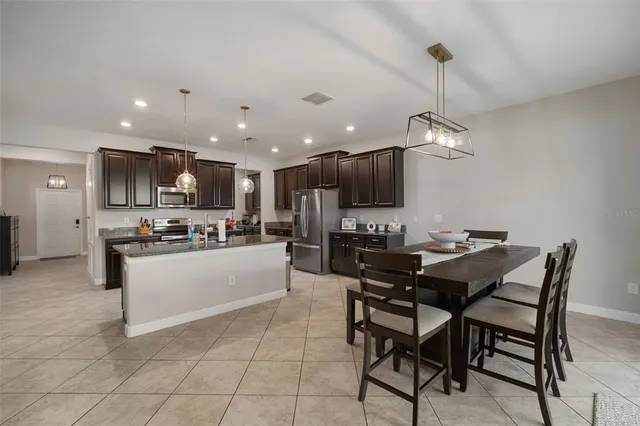 a kitchen with stainless steel appliances kitchen island granite countertop a sink and a refrigerator