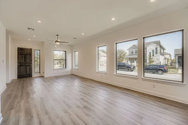 a view of an empty room with a window and wooden floor