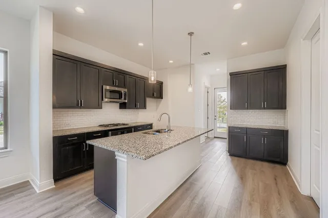 a large kitchen with stainless steel appliances granite countertop a stove a sink and a refrigerator