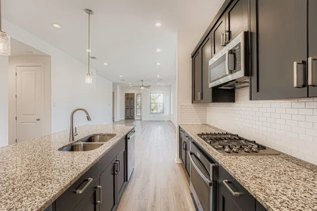 a kitchen with stainless steel appliances granite countertop a sink a stove and a wooden floors