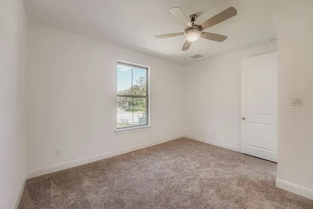 an empty room with windows and fan