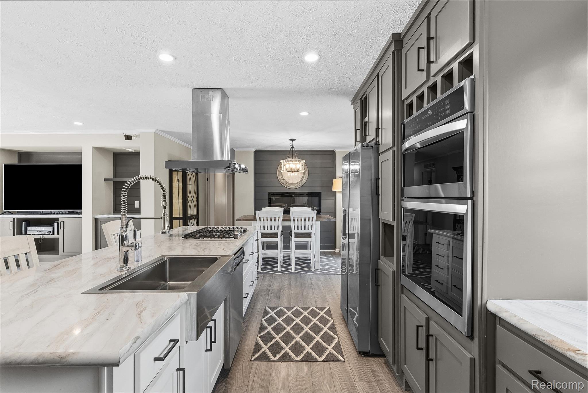 6450 Prince Boulevard Fenton, MI 48430 - Photo 15 of 31 Gourmet kitchen featuring a large island with a farmhouse sink, stainless steel appliances, abundant cabinetry, and wood-finish flooring