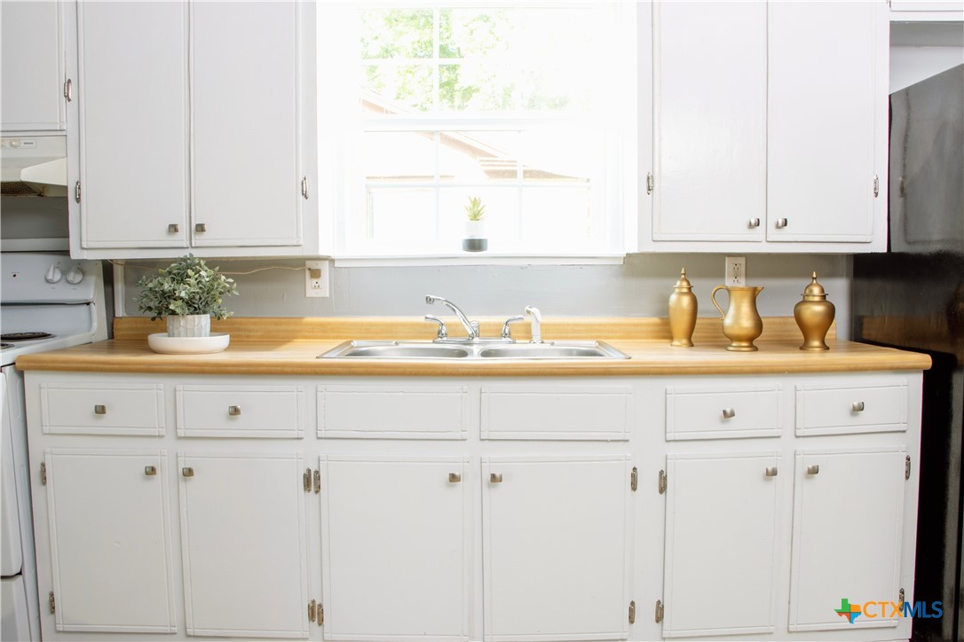 1407 South 7th Street Temple, TX 76504 - Photo 8 of 36 a kitchen with white cabinets and a sink