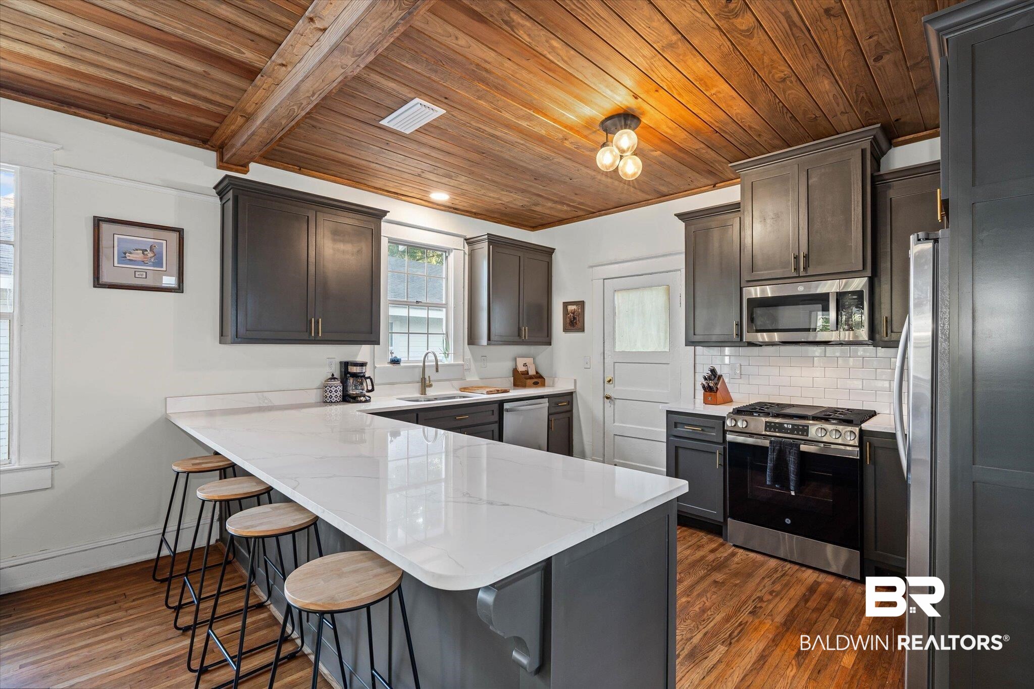 11 South Lafayette Street Mobile, AL 36604 - Photo 8 of 20 Kitchen featuring appliances with stainless steel finishes, a kitchen breakfast bar, a peninsula, tasteful backsplash, and wooden ceiling