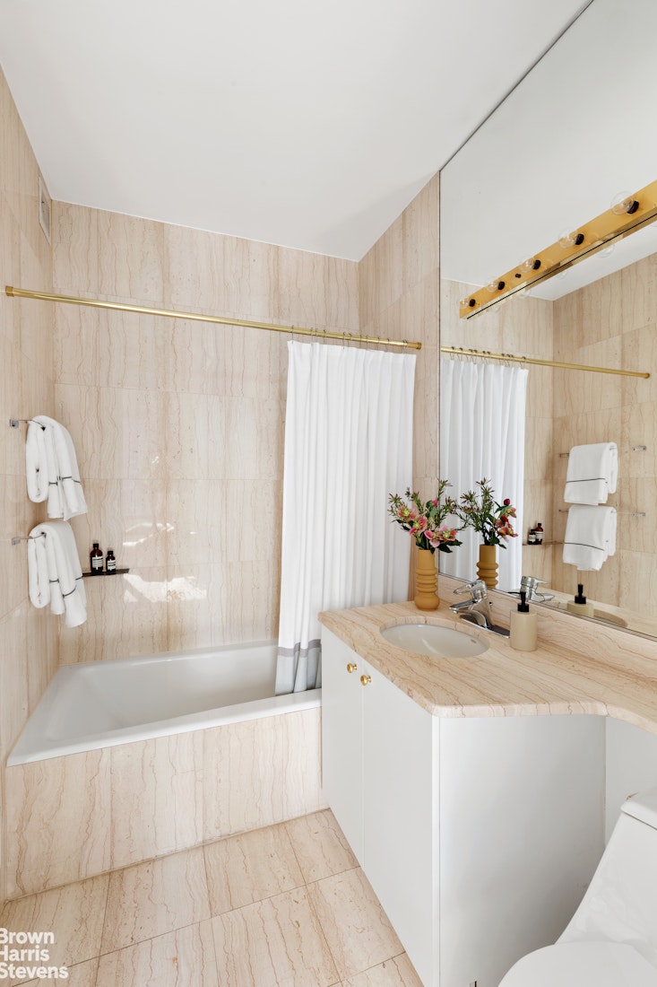 150 Columbus Avenue, Unit 18F Manhattan, NY 10023 - Photo 18 of 22 a bathroom with a tub sink and mirror