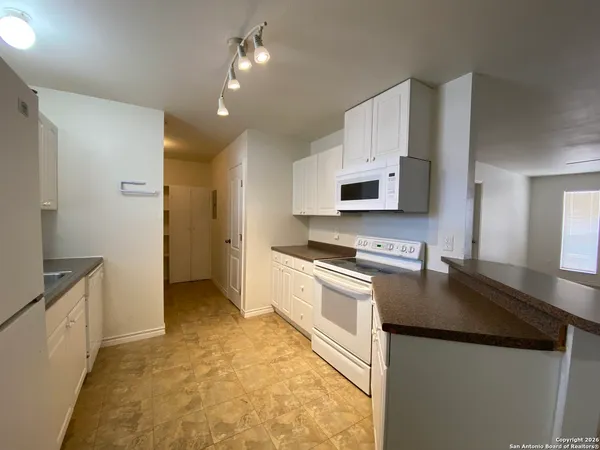 a kitchen with granite countertop a refrigerator a stove top oven and a sink