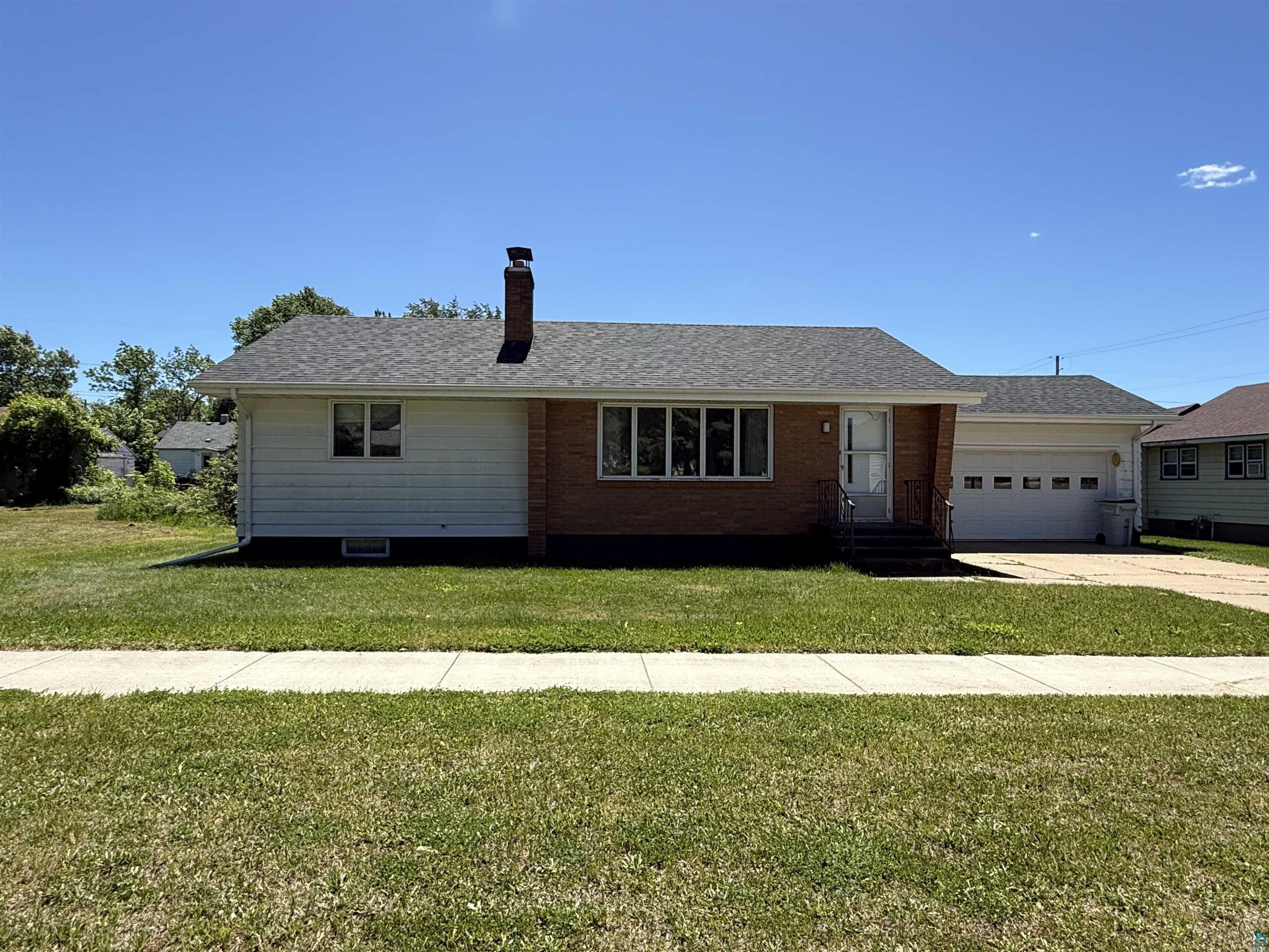 607 3rd Street Northeast Chisholm, MN 55719 - Photo 1 of 32 Ranch-style residence featuring a brick and siding exterior, an attached garage, a front entry with steps, and a shingled roof