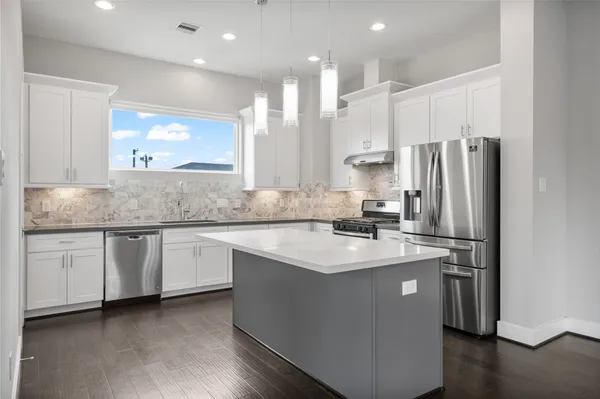 a kitchen with stainless steel appliances granite countertop a refrigerator a sink and a stove