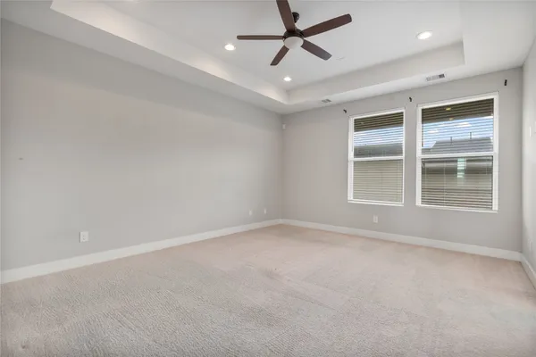 an empty room with ceiling fan and windows