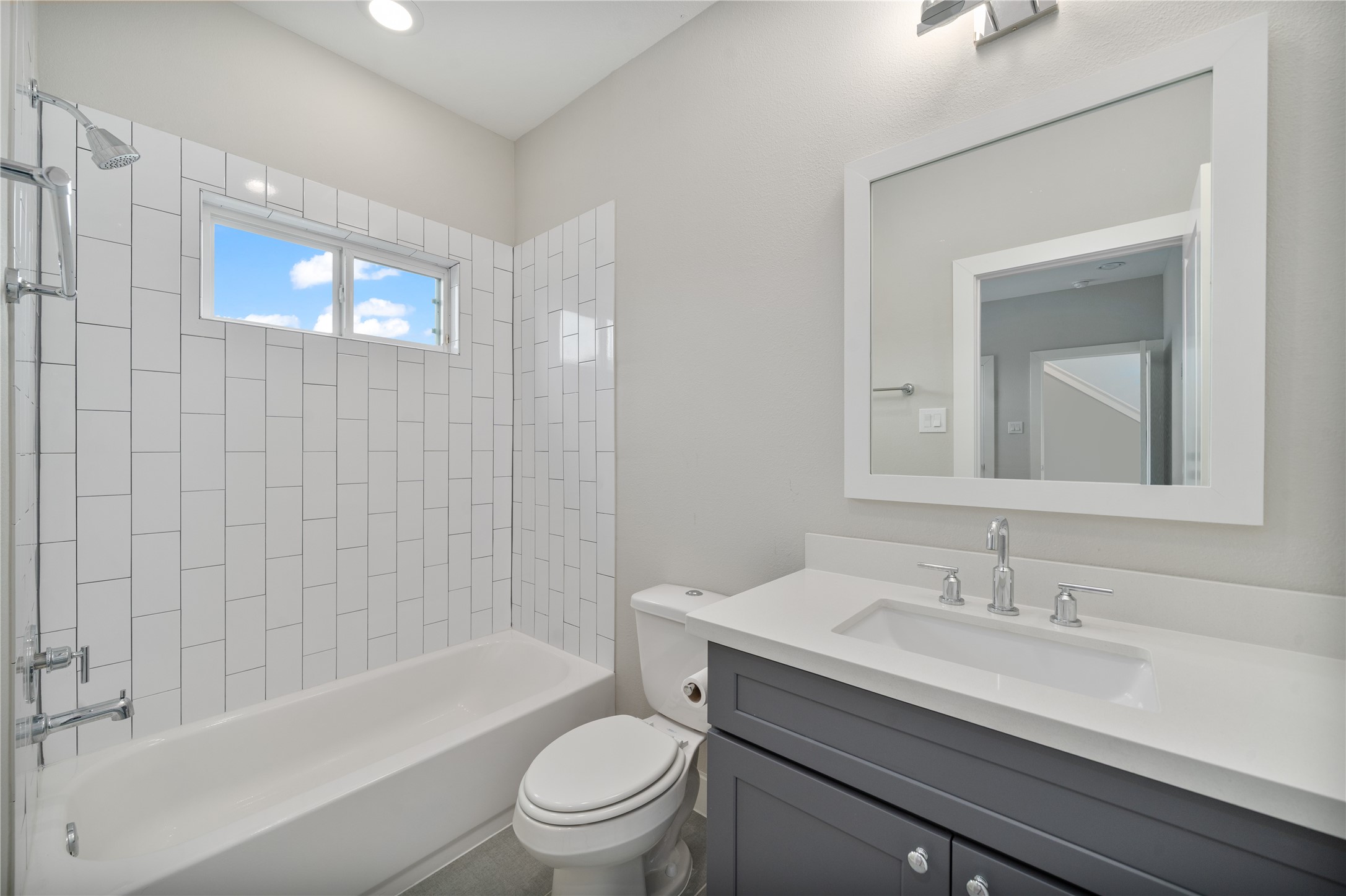 2510 Tuam Street, Unit G Houston, TX 77004 - Photo 10 of 40 a bathroom with a granite countertop toilet a sink a mirror a bathtub and shower