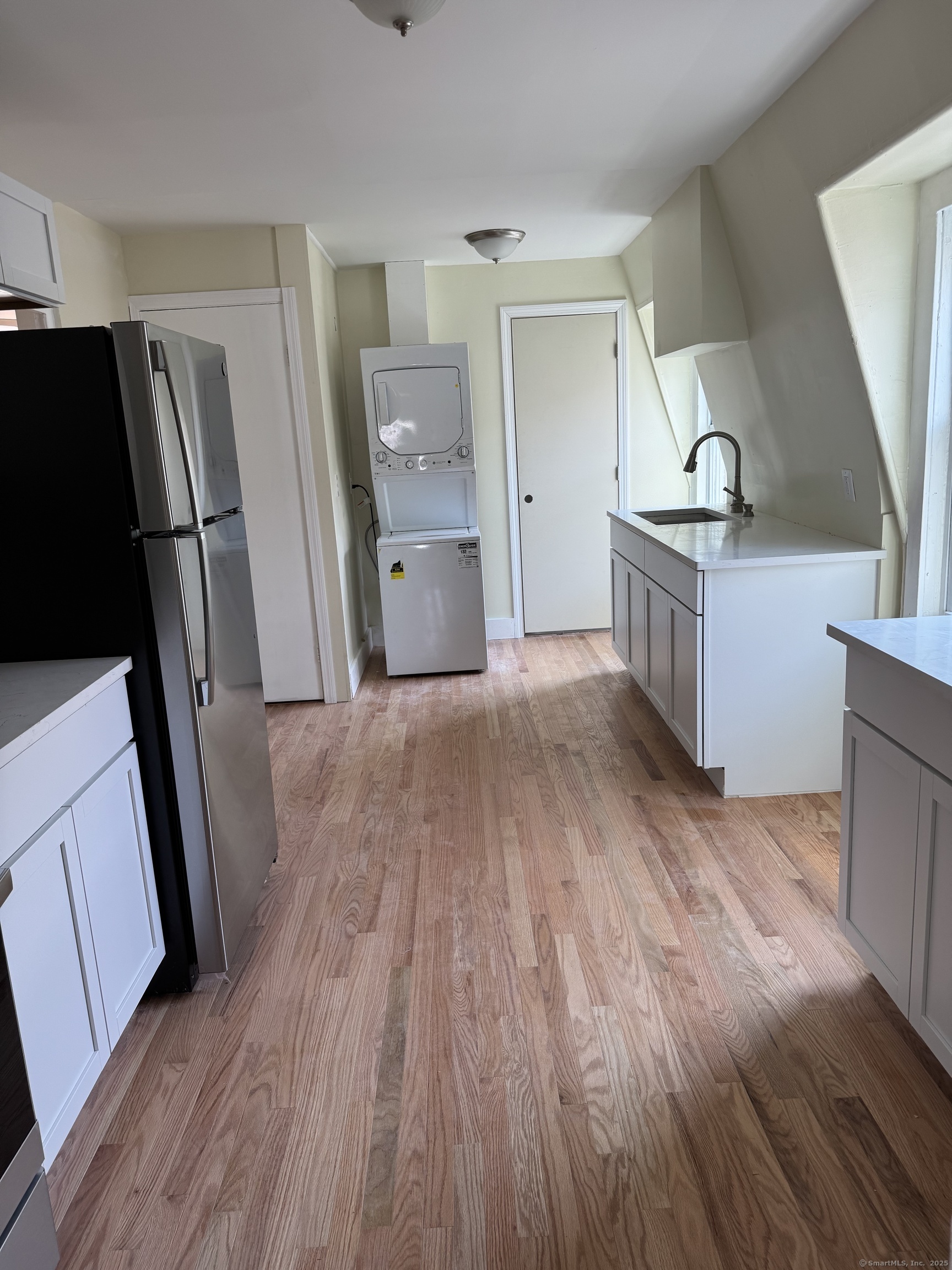 a kitchen with granite countertop a refrigerator and wooden floor