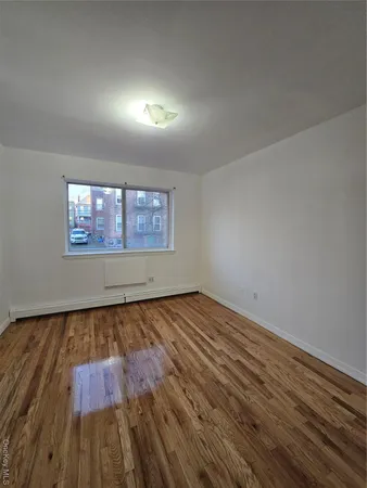 a view of an empty room and wooden floor and window