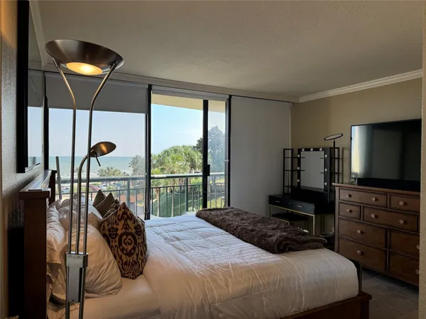 a bedroom with a bed and large flat tv screen on dresser