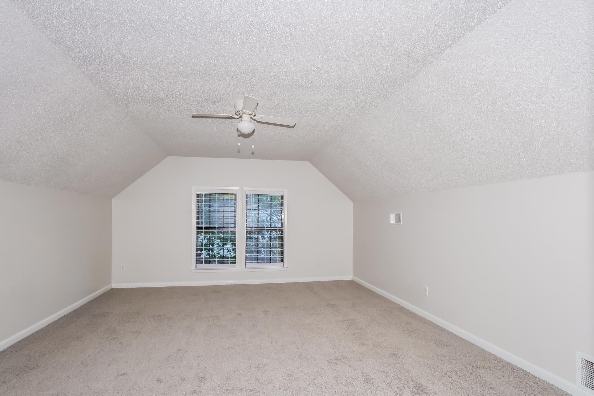 1441 Sandy Stone Lane Memphis, TN 38016 - Photo 15 of 18 Additional living space featuring a textured ceiling, light colored carpet, vaulted ceiling, and a ceiling fan