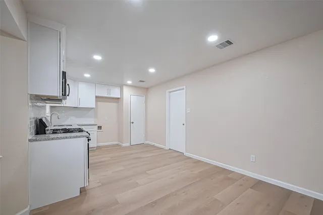 a kitchen with stainless steel appliances granite countertop a stove a sink and a refrigerator with wooden floor