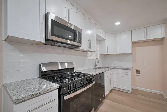 a kitchen with stainless steel appliances granite countertop white cabinets and black stove top oven