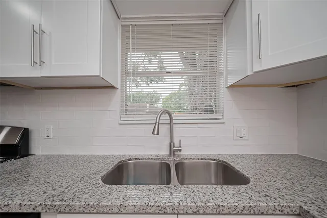 a kitchen with granite countertop a sink and a wooden floor