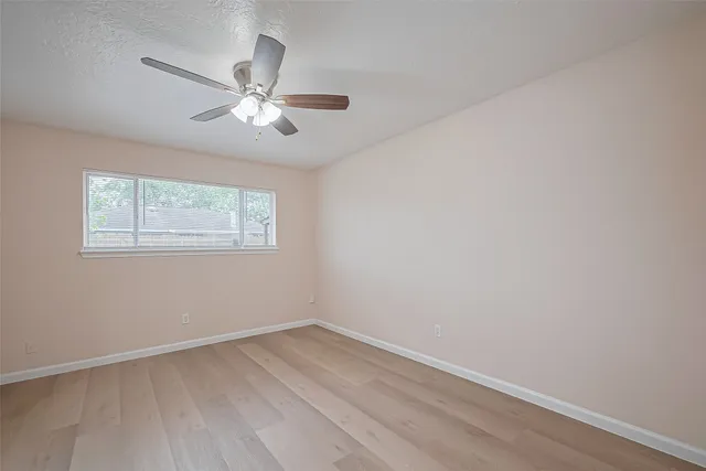 an empty room with a window and a fan