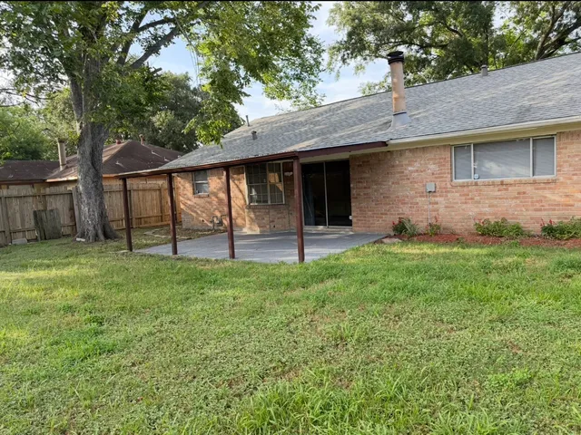 a view of a house with a yard and a large tree