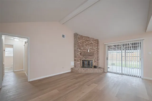 wooden floor fireplace and windows in an empty room
