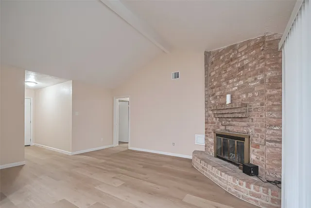 a view of a livingroom with wooden floor and a fireplace