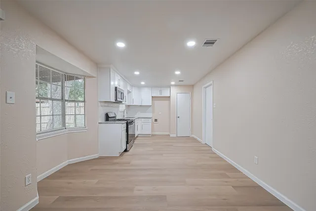 a view of empty room with windows and wardrobe