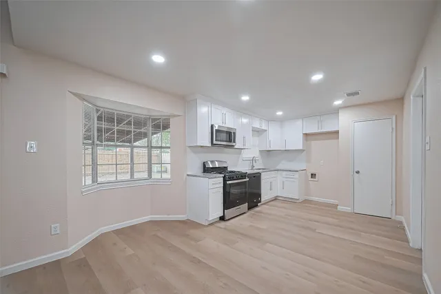 a large kitchen with granite countertop a stove top oven a sink dishwasher a refrigerator and cabinets with wooden floor