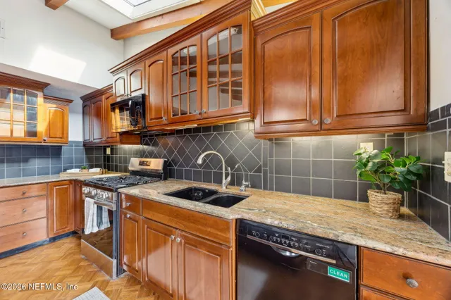 a kitchen with stainless steel appliances granite countertop a sink a stove and cabinets