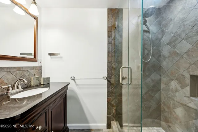 a bathroom with a granite countertop shower sink and mirror