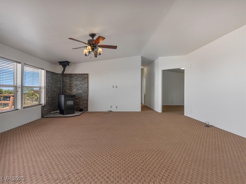 70 West Bonanza Road Las Vegas, NV 89124 - Photo 12 of 71 Unfurnished living room with carpet flooring, a wood stove, a ceiling fan, and lofted ceiling