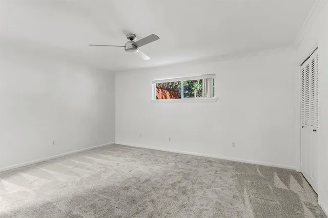 an empty room with a ceiling fan and a window