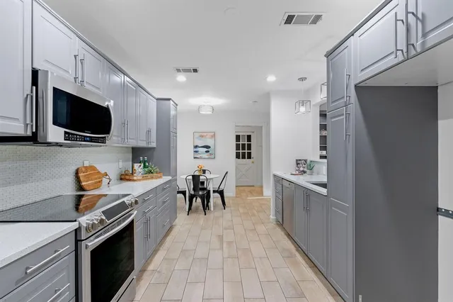 a kitchen with granite countertop a sink a stove top oven and cabinetry