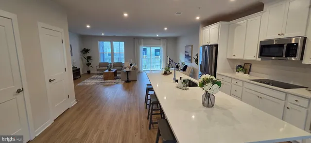 a large kitchen with sink a refrigerator and wooden floor